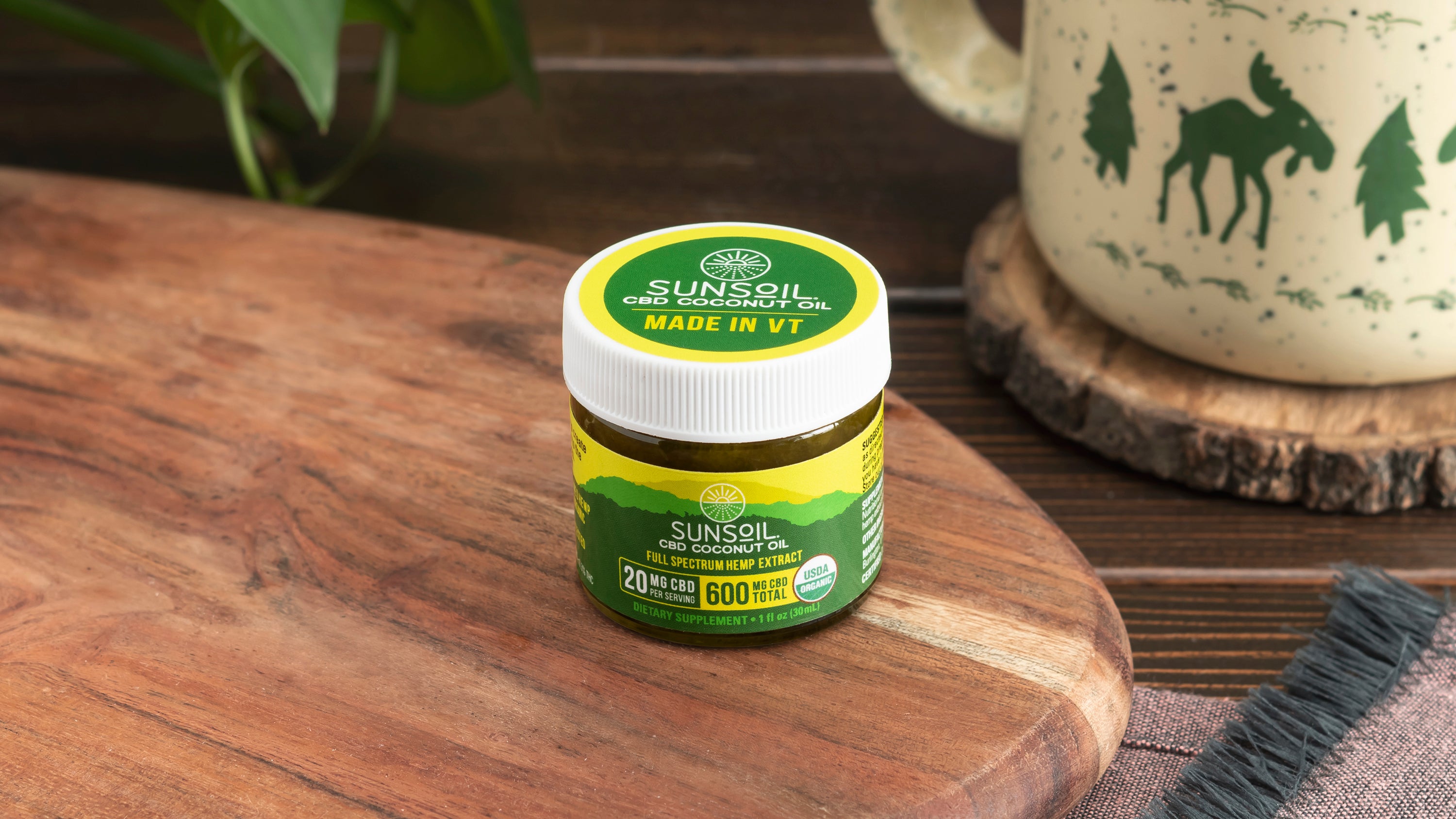 Sunsoil CBD coconut oil jar on a wooden cutting board