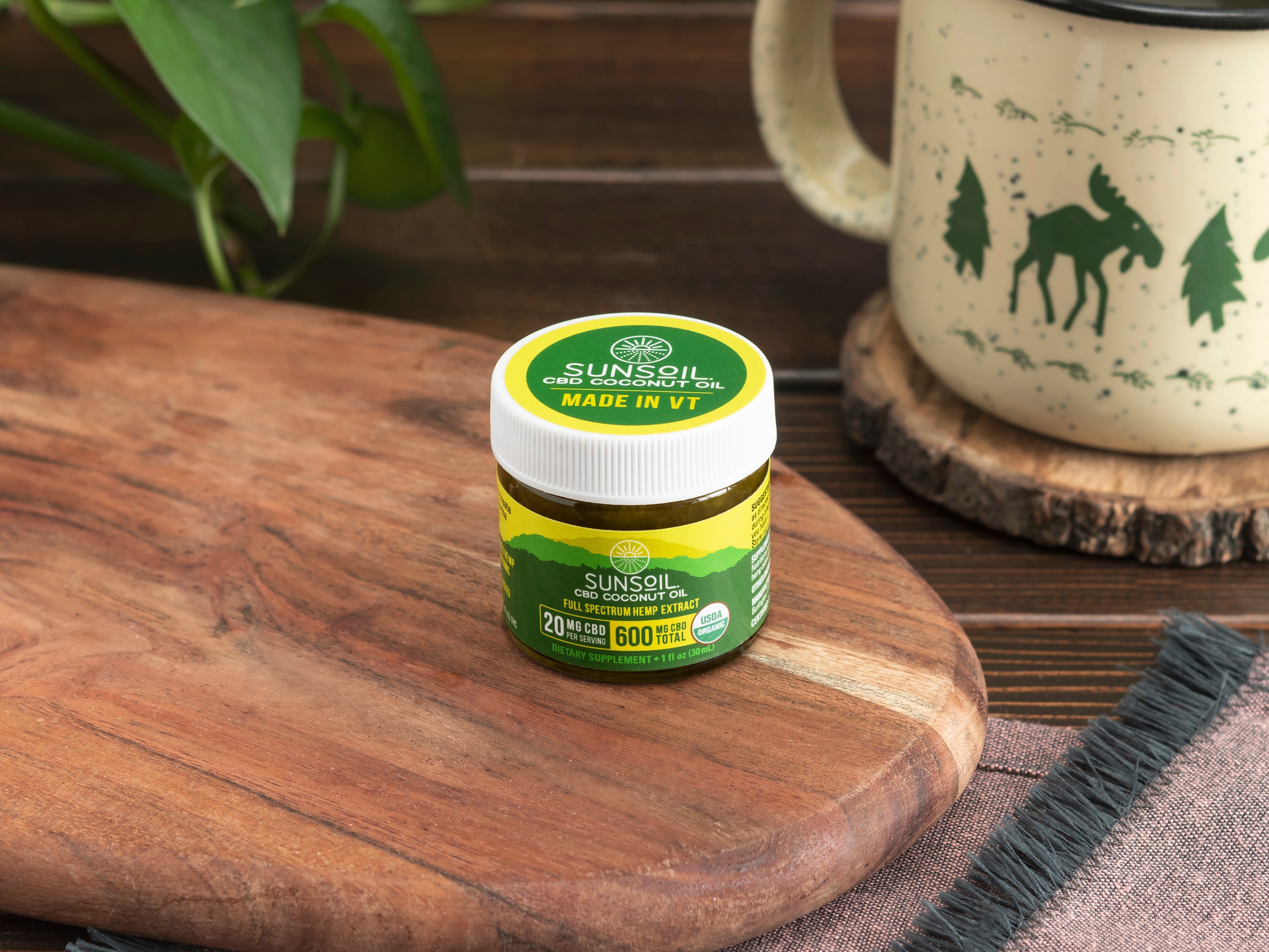 Sunsoil CBD coconut oil jar on a wooden cutting board