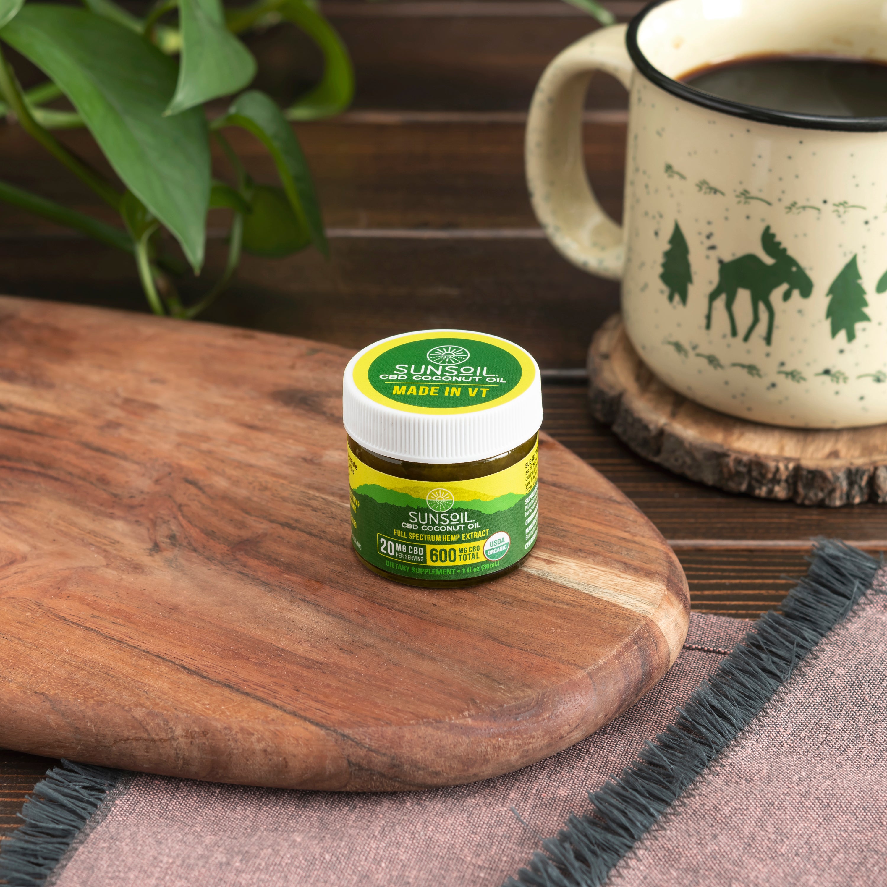 Sunsoil CBD coconut oil jar on a wooden cutting board